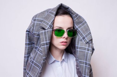 Yeşil gözlüklü ve gri ekose elbiseli kadın.
