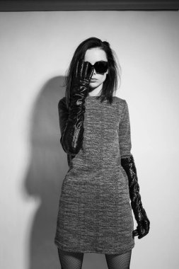 Kadın elini, uzun eldivenleri ve elbisesi ile yüzünü kapatıyor. Siyah beyaz dikey fotoğrafçılık.