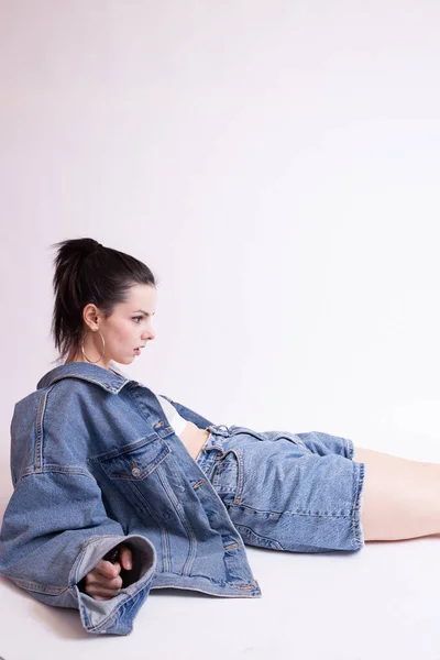 woman in denim jacket and shorts, on white studio background