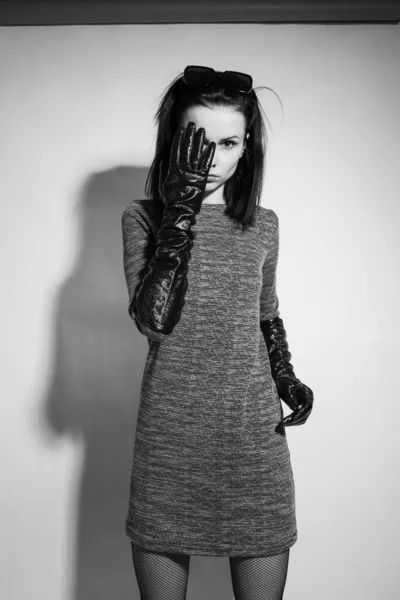 woman covers her face with her hand, in long gloves and a dress, black and white vertical photography