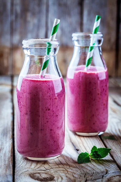 Juicy blackberry smoothies in glass bottles — Stock Photo, Image