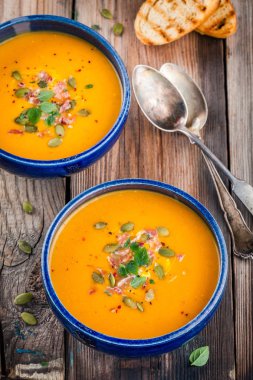 homemade autumn butternut squash soup with pumpkin seeds, bacon and basil clipart