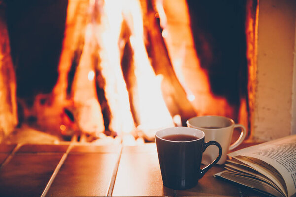 Two cups and Open book by Christmas Fireplace