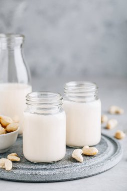 Gri taş zemin üzerinde cam içinde kaju fıstığı sütü ve kopyalama alanı