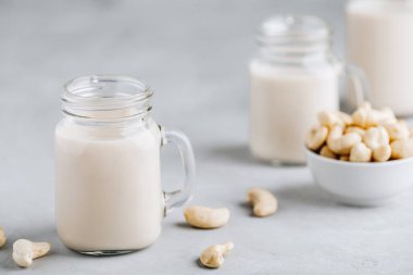 Gri taş zemin üzerinde cam içinde kaju fıstığı sütü ve kopyalama alanı