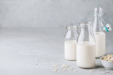 Bardakta yulaf sütü. Gri taş zemin üzerinde süt olmayan vegan yulaf sütü, kopyalama alanı.