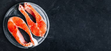 Pişirmek için taze çiğ somon bifteği. Üst görünüm, karanlık taş arkaplanda boşluk kopyala.