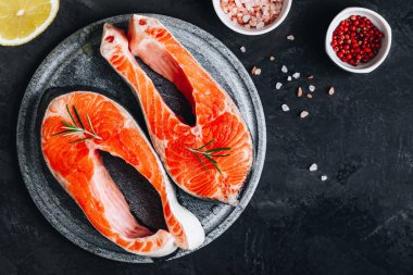 Pişirmek için taze çiğ somon bifteği. Üst görünüm, karanlık taş arkaplanda boşluk kopyala.