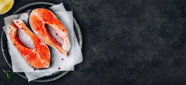 Pişirmek için taze çiğ somon bifteği. Üst görünüm, karanlık taş arkaplanda boşluk kopyala.