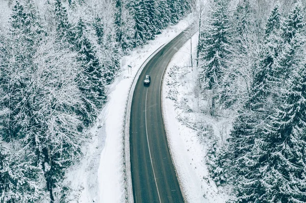 森の中に車や雪に覆われた木と冬の道路の空中ビュー — ストック写真