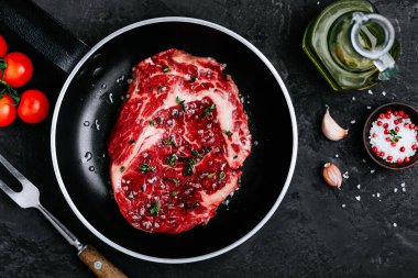 Pişirme, barbekü ve ızgara için hazırlanmış, koyu taşlı arka planda kızarmış tavada taze çiğ pirzola. Üst görünüm, alanı kopyala