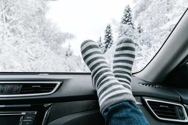 女人的脚穿着保暖的袜子在汽车仪表盘上 冬雪时间 旅游理念 — 图库照片
