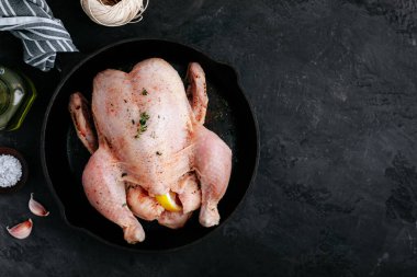 Çiğ tavuk pişirmeye hazır. Koyu taşlı arka planda serbest organik tavuk. Üst görünüm, boşluğu kopyala.