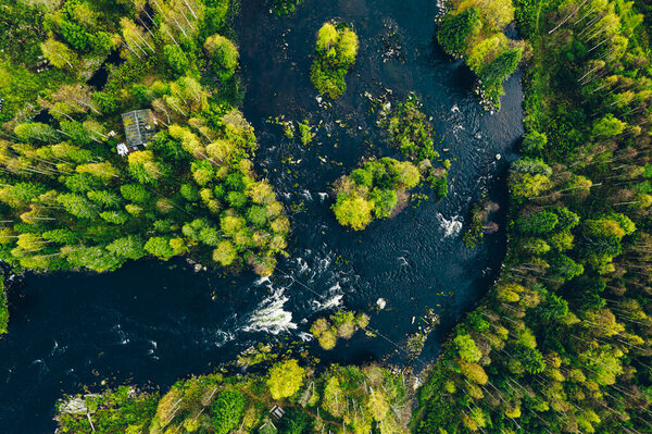 Aerial view of fast blue river in beautiful green spring forest in Finland.