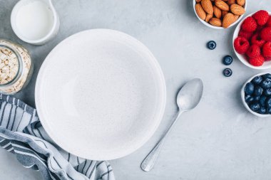 Kahvaltı için malzemeler. Kahvaltı gevreği ve çeşitli lezzetli malzemeler. Yulaf, yabanmersini, ahududu, badem ve sütlü gri taş kaplama beton arka plan, fotokopi alanı, üst manzara