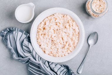 Yulaf ezmesi. Sağlıklı kahvaltı gevreği kasesi gri taşlı arka planda yulaf ezmesi, kopyalama alanı, üst görünüm.