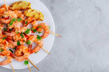 Gri taşlı arka planda ızgara limonlu karides şişi. Kopyalama alanı olan üst görünüm