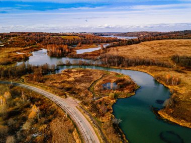 Altın renkli sonbahar veya sonbahar ormanlarındaki kıvrımlı nehir ve yol manzarası