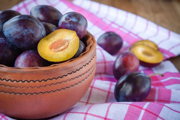 Organic ripe plums in a clay bowl — Stock Photo, Image