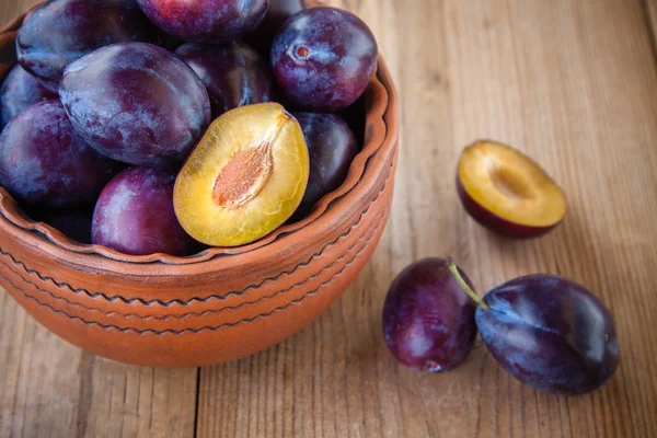 Organic ripe plums in a clay bowl — Stock Photo, Image