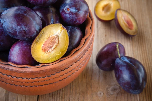 Organic ripe plums in a clay bowl — Stock Photo, Image