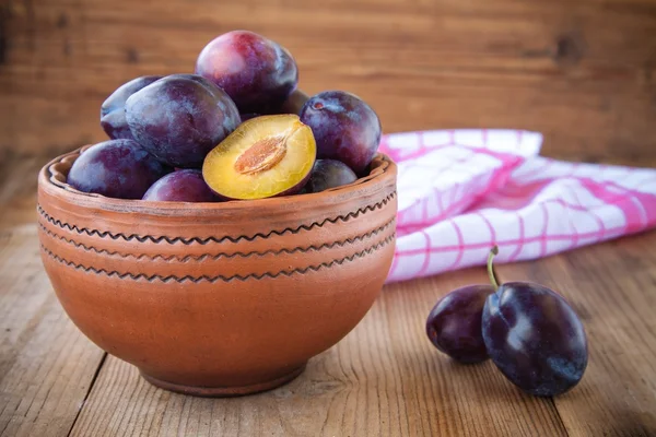 Organic ripe plums in a clay bowl — Stock Photo, Image