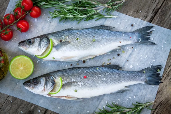 Two raw seabass with lime, cherry tomatoes and rosemary — Stock Photo, Image