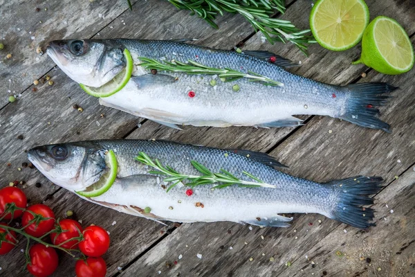 Two raw seabass with lime, cherry tomatoes and rosemary — Stock Photo, Image