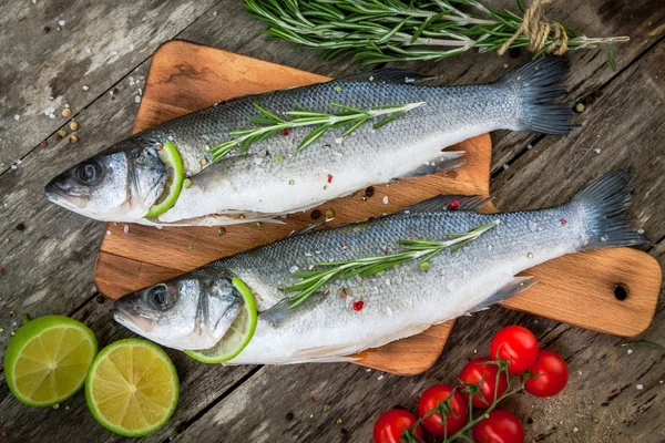 Two raw seabass with lime, cherry tomatoes and rosemary — Stock Photo, Image