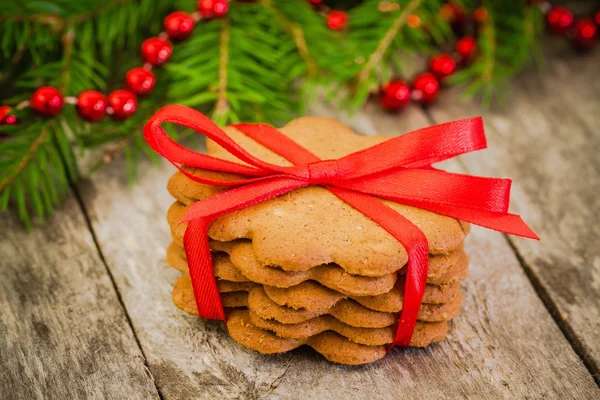 Christmas gingerbread cookies on a rustic wooden background with red ribbon — Stock Photo, Image