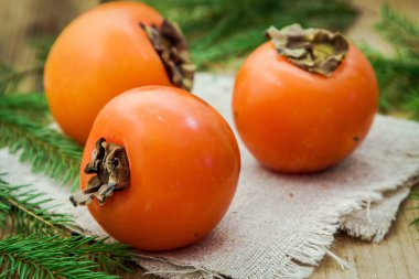 Ahşap zemin üzerinde üç taze organik Trabzon hurması