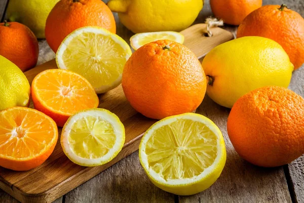 Ripe mandarins and lemons on a cutting board — Stock Photo, Image