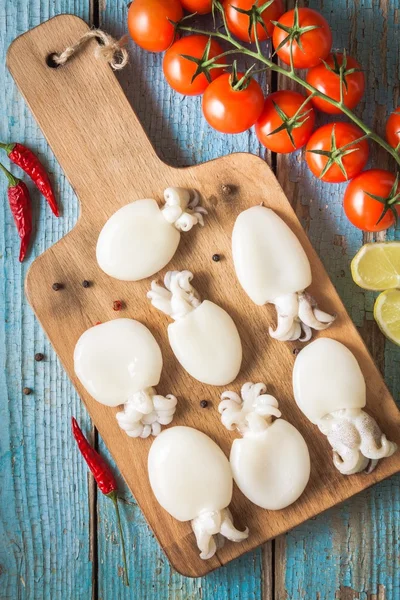 Domates ile bir kesme tahtası üzerinde ham bebekler mürekkep balığı