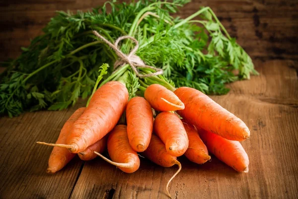 Fresh organic carrots bunch on wooden background — Stock Photo, Image