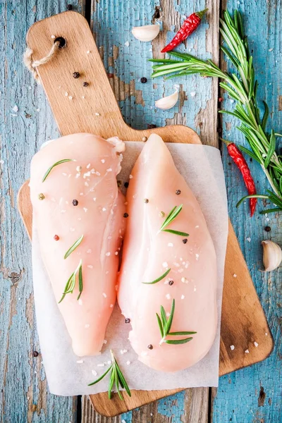 Rohes Hühnerfilet mit Knoblauch, Pfeffer und Rosmarin auf rustikalem Hintergrund — Stockfoto