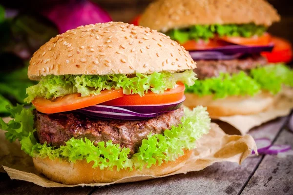 Dos hamburguesas caseras con lechuga verde fresca, tomates y cebollas rojas — Foto de Stock