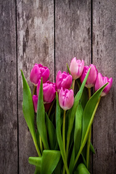 Strauß lila Tulpen auf einem hölzernen Hintergrund — Stockfoto