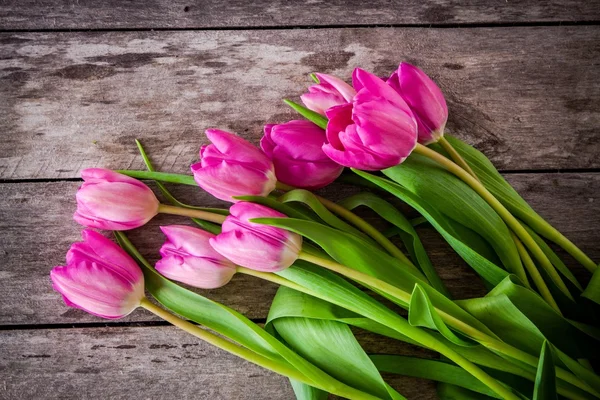 Csokor, világos rózsaszín tulipánok a fából készült háttér — Stock Fotó