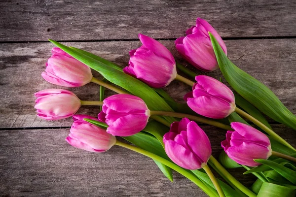 Ramo de tulipanes morados sobre un fondo de madera — Foto de Stock