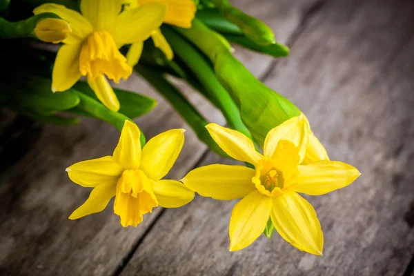 Ramo de narcisos amarillo brillante primer plano sobre un fondo rústico de madera — Foto de Stock