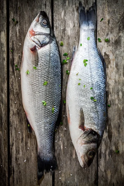 Two raw seabass with fresh thyme on wooden table — Stock Photo, Image