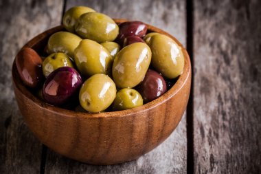 mixed olives in a wooden bowl closeup on a rustic table  clipart