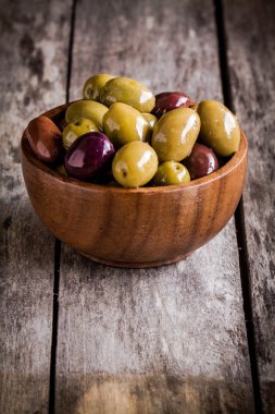 rustik bir tabloda bir kasede karışık zeytin