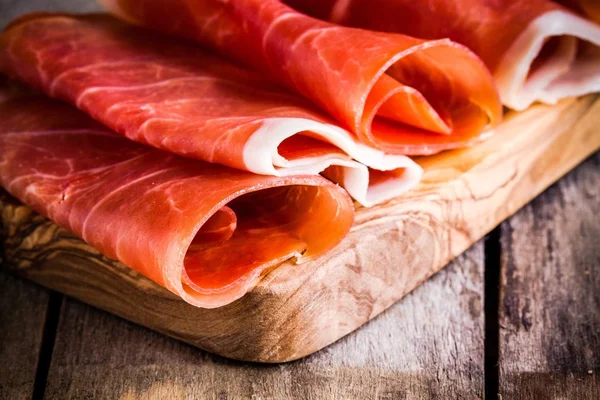 Thin slices of prosciutto closeup on a cutting board — Stock Photo, Image
