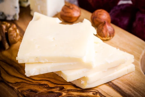 Queso emmental de cerca con nueces en una tabla de madera — Foto de Stock