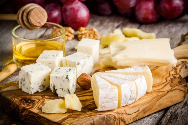 Mix Cheese: Emmental, Camembert, Parmesan, blue cheese, bread sticks, walnuts, hazelnuts, honey, grapes — Stock Photo, Image