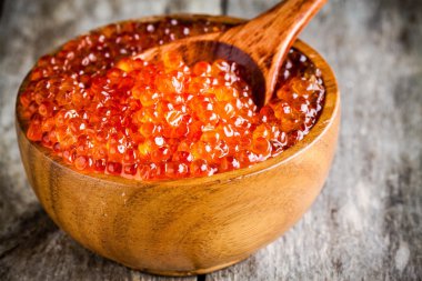 fresh red caviar in a wooden bowl with a spoonful closeup clipart