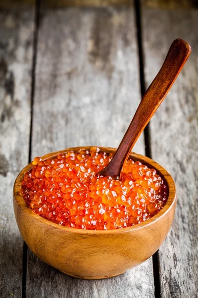 Fresh red caviar in a wooden bowl with a spoon — Stock Photo, Image