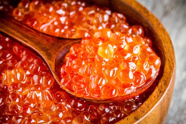 Fresh red caviar in a wooden bowl with a spoonful closeup — Stock Photo, Image