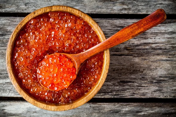 Fresh red caviar in a wooden bowl with a spoonful — Stock Photo, Image